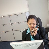 A receptionist at her desk, on the phone.
